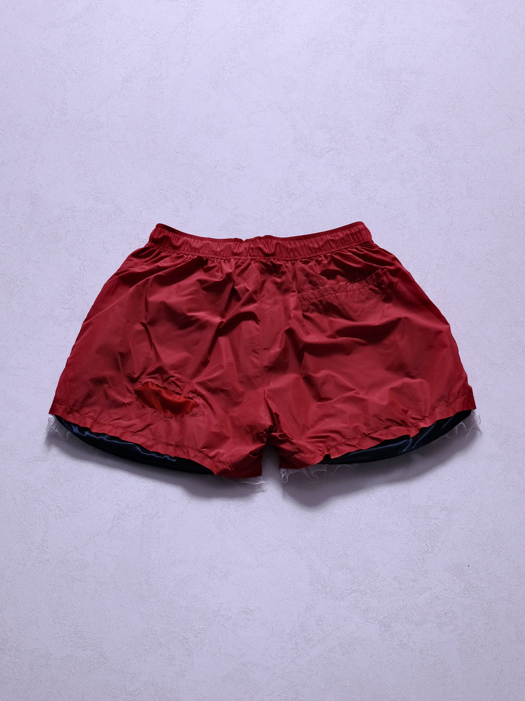 One-of-one upcycled nylon shorts, back product shot showing satin fabric and orb-shaped mesh cutout